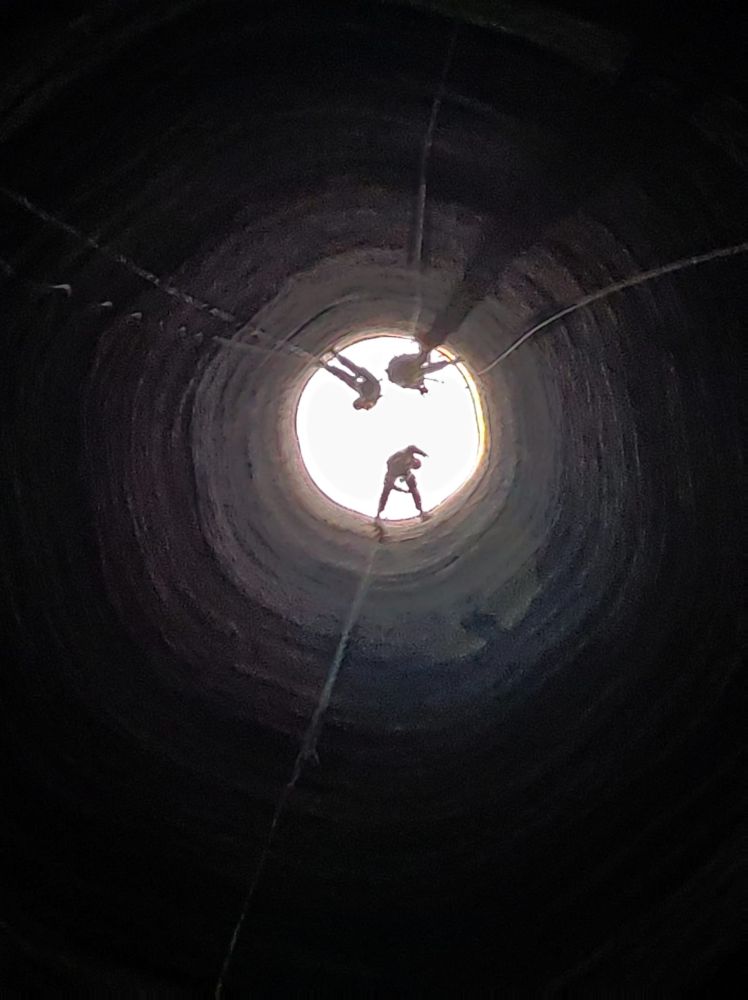 Vue de l'intérieur de la cheminée où l'on voit nos trois cordistes en action à une quinzaine de mètres de distance.
