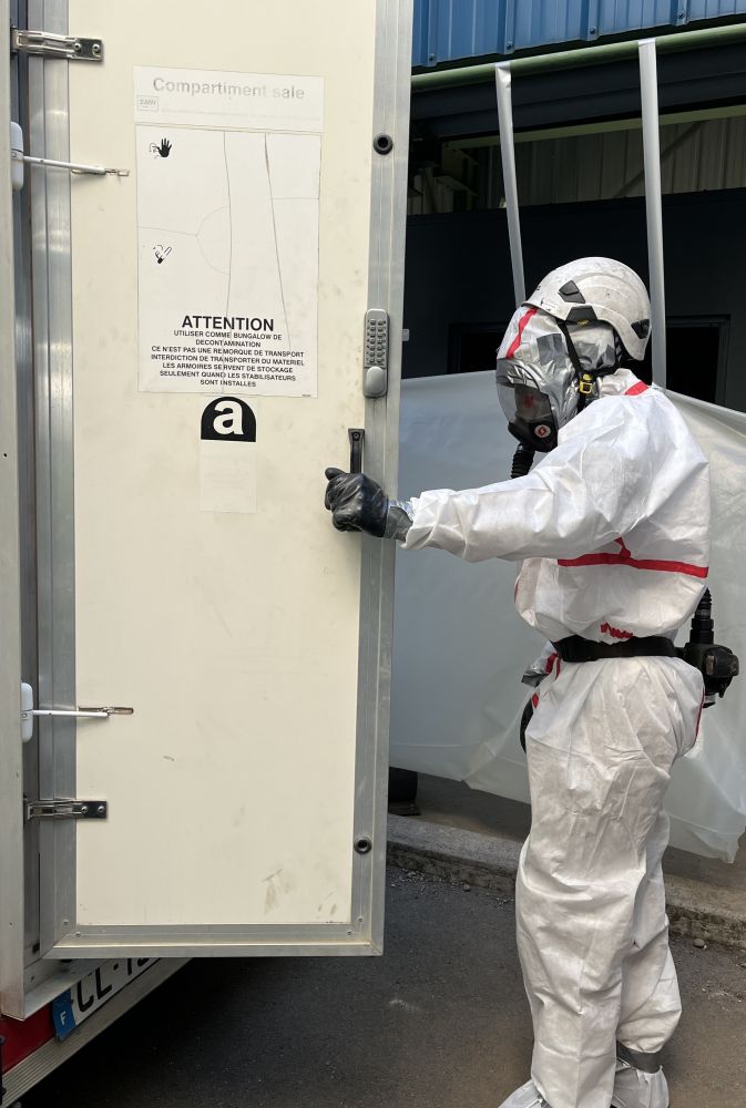 Technicien cordiste de BOTHIER entrant dans une Unité Mobile de Décontamination amiante